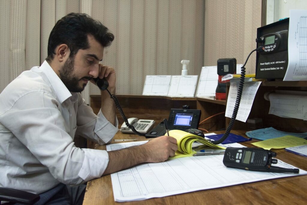 Um Homem Sentado Em Uma Mesa Falando Em Um Telefone xyCT3RHdCTs