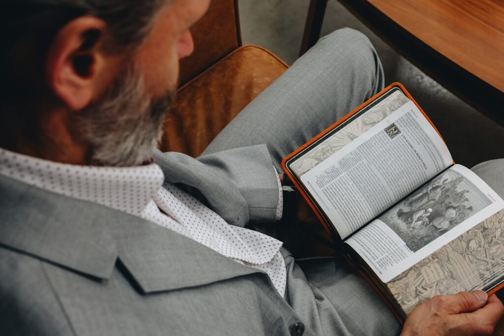 Um Homem Sentando Em Um Cadeira Leitura Um Livro LxeXIsnIvb8