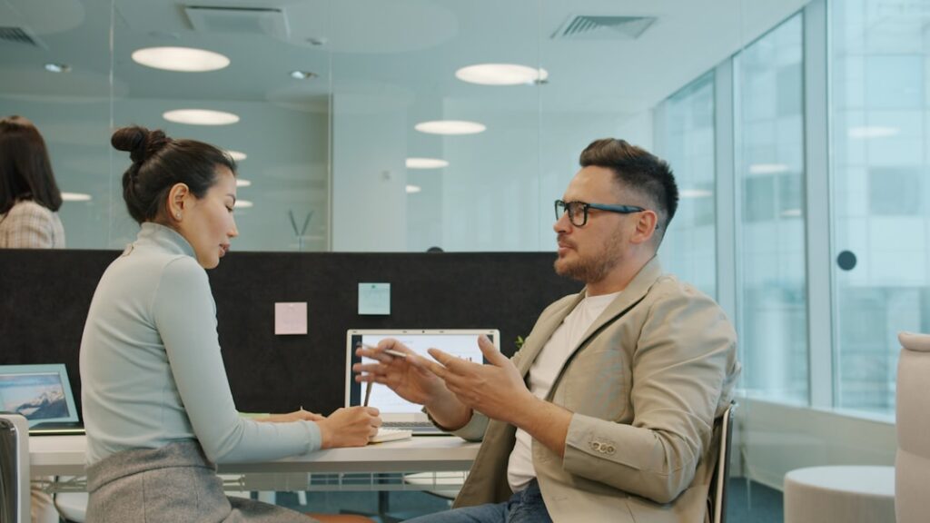 Dois Colegas Discutindo O Trabalho Em Um Escritorio Moderno E3TJIo5E9Gg