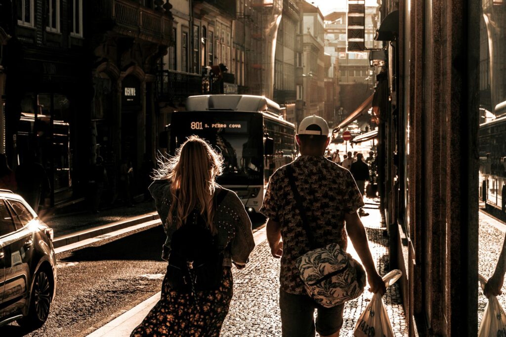 A couple strolls through Porto, Portugal, on a bustling city street during sunset.