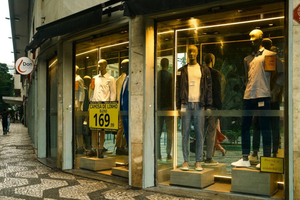 Stylish men's fashion display in a São Paulo storefront with mannequins showcasing modern apparel.
