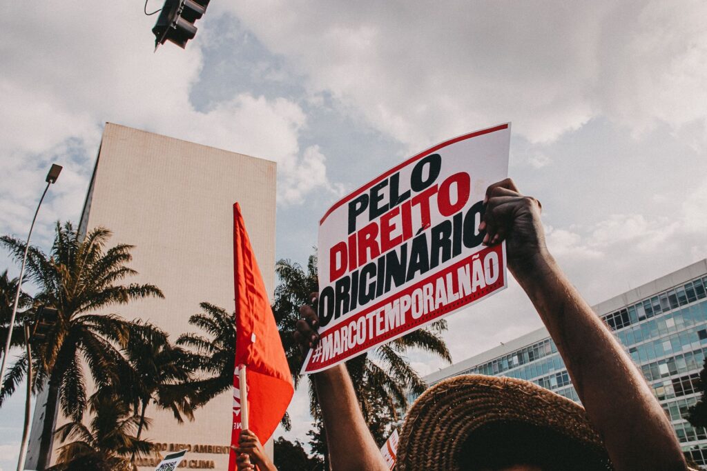 Demonstrators holding signs against Marco Temporal in city protest.
